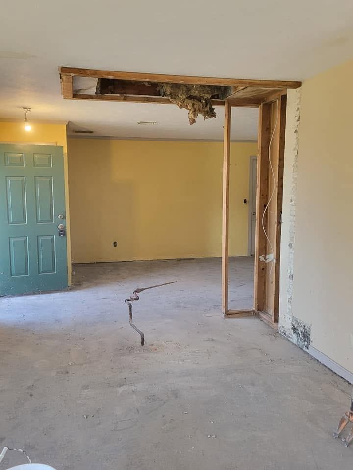 Fireplace Removal After After fireplace removal: open ceiling rough-in with exposed framing in yellow-walled living room.